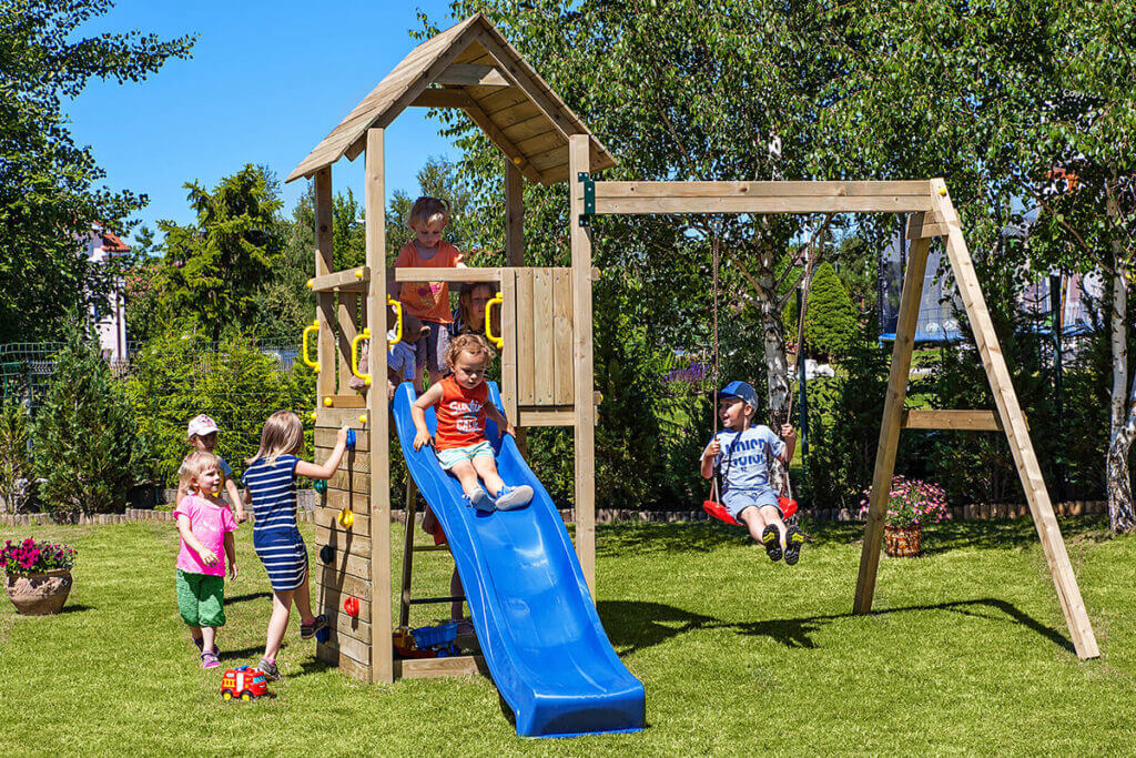 plac zabaw w ogródku z bawiącymi się dziećmi 