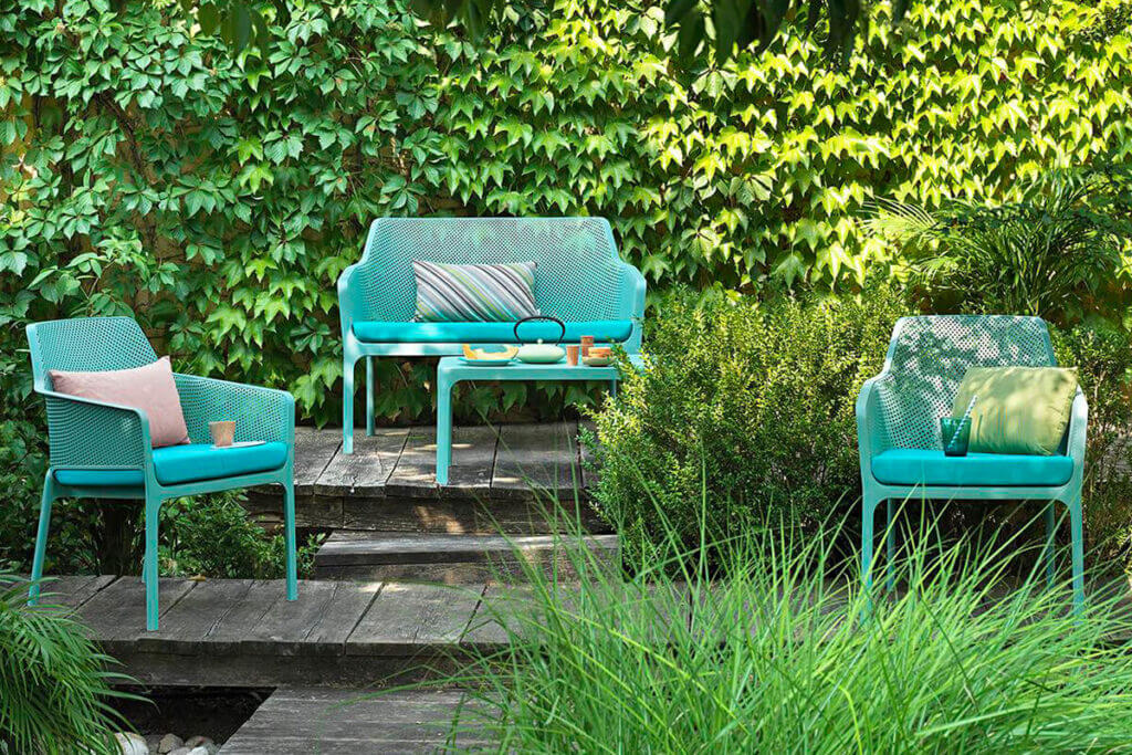 krzesła ogrodowe z sofą pośród zieleni 