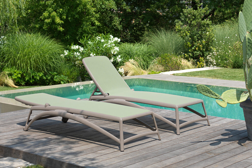 stylowe leżaki ogrodowe na drewnianym podeście przy basenie 
