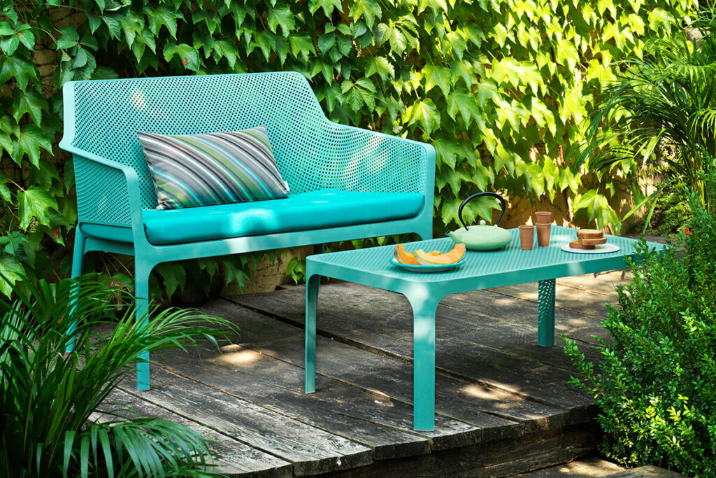 ławka ogrodowa z wygodnymi poduszkami i stolikiem na drewnianym tarasie