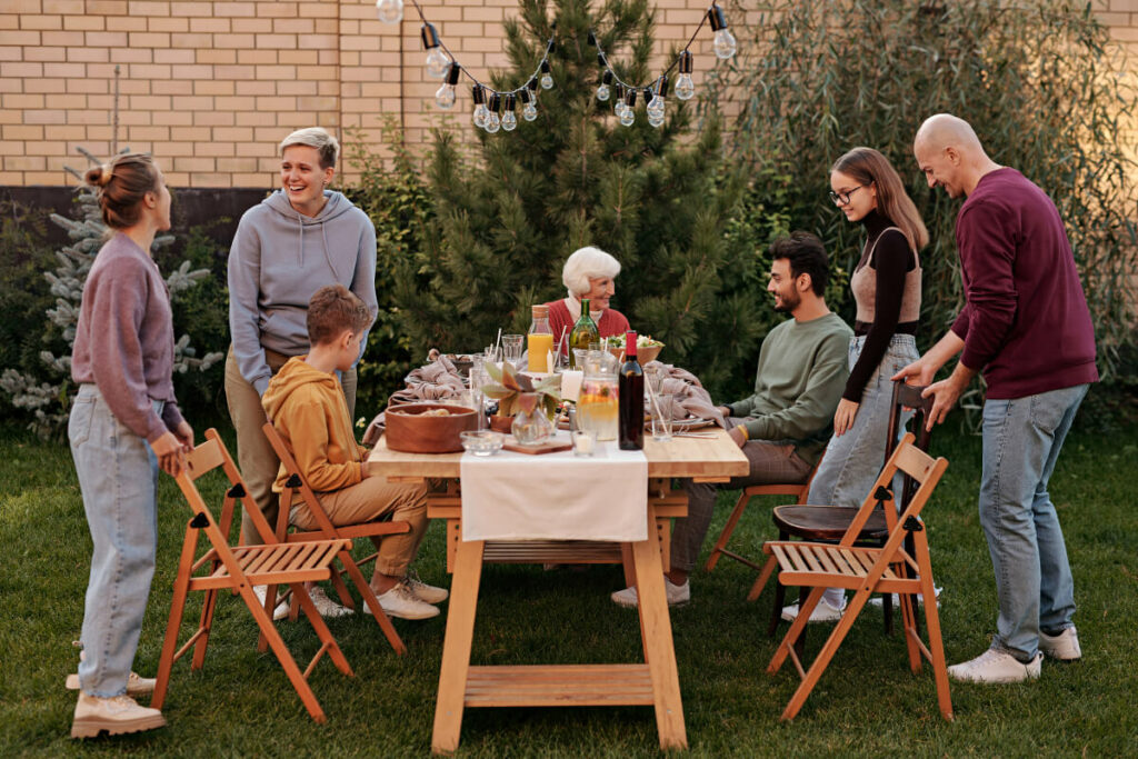 jadalniany zestaw mebli do ogrodu wykonany z drewna, rodzina biesiadująca przy stole w ogrodzie 