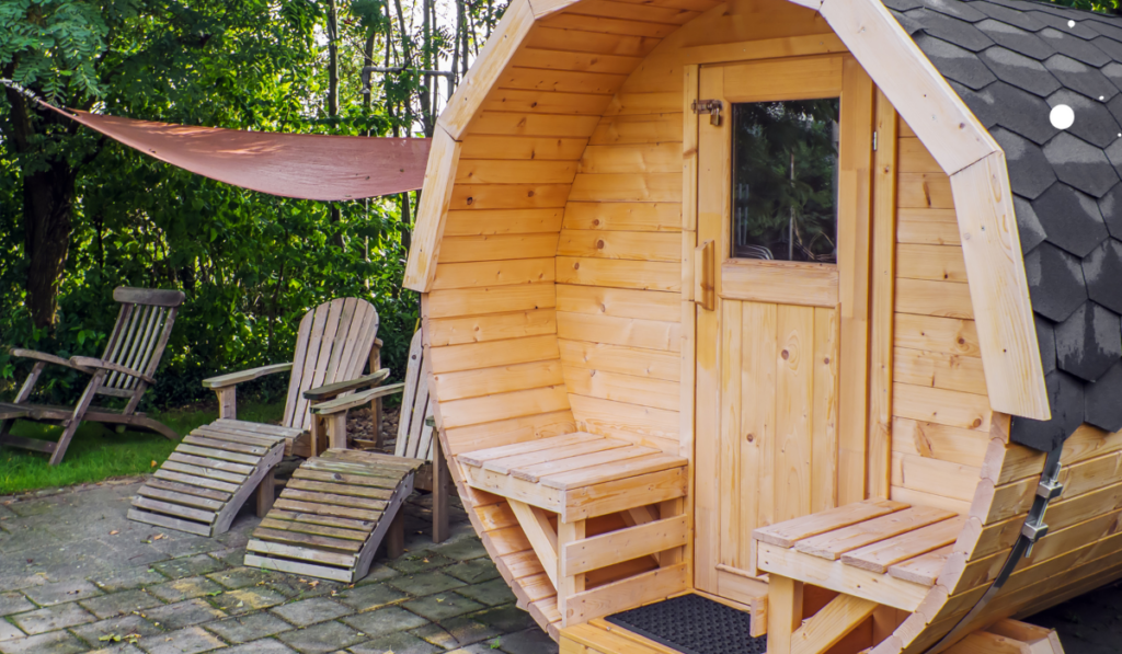 Drewniana sauna ogrodowa ustawiona w ogrodzie z drewnianymi leżakami do odpoczynku 