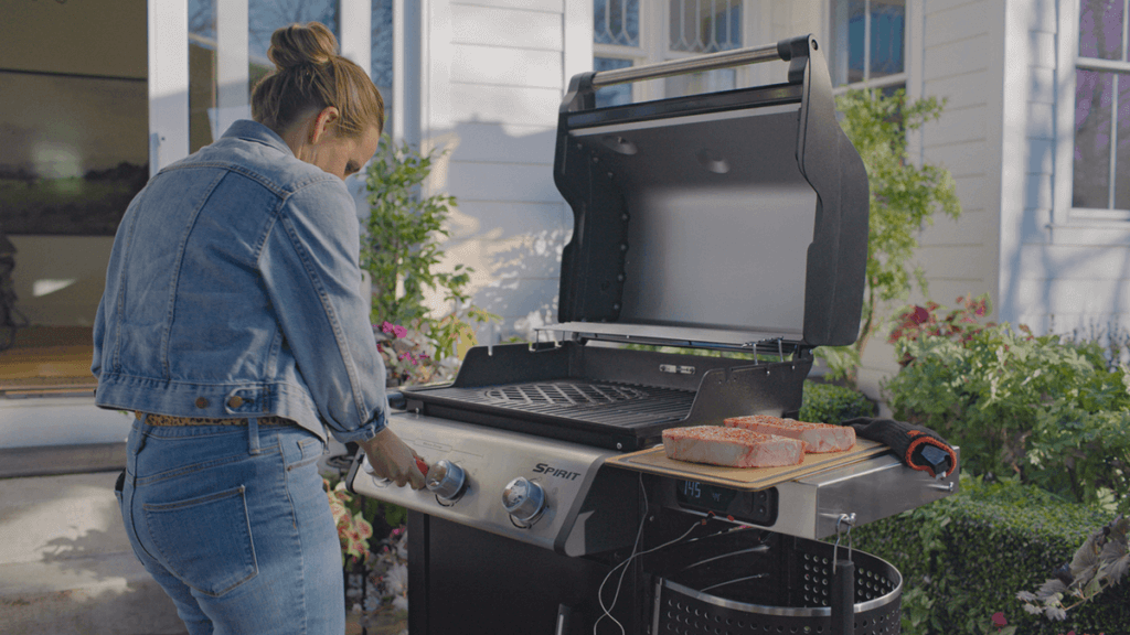 grill ogrodowy z aplikacją - kobieta przygotowująca grilla inteligentnego do gotowania na świeżym powietrzu 