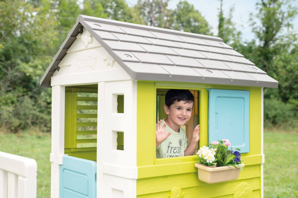 Chłopiec wyglądający z za okna domku na palach smoby
