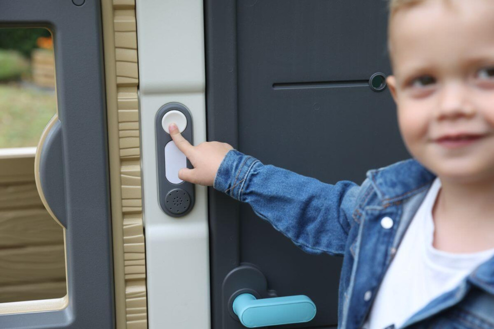 Chłopiec wskazujący na dzwonek do drzwi do domu smoby