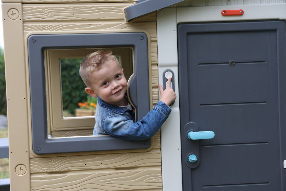 Chłopiec pokazujący na dzwonek do drzwi do domu smoby