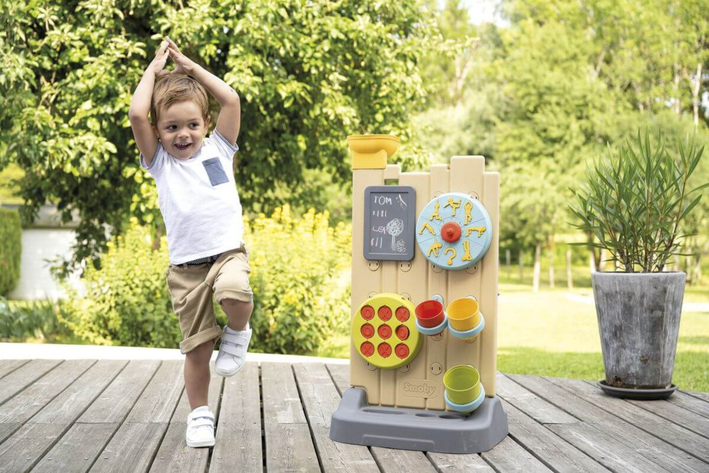 Chłopiec podskakujący przy ogrodowej ściance aktywności na ogrodzie