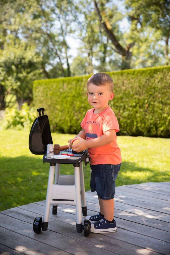 Chłopiec bawiący się przy zestawie do grillowania dla dzieci smoby
