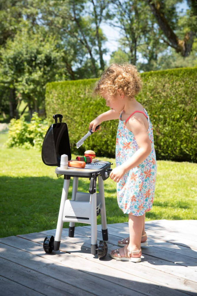 Dziewczynka bawi się przy zestawie do grillowania dla dzieci smoby