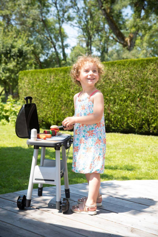 Dziewczynka obok zestawu do grillowania dla dzieci smoby