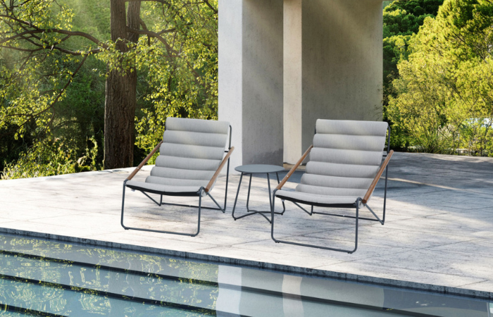 dwa szare krzesła z drewnianymi podkłokietnikami ustawione na tarasie nad basenem