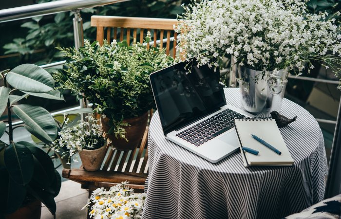 Piękny taras lub balkon z małym stołem, laptopem i kwiatami