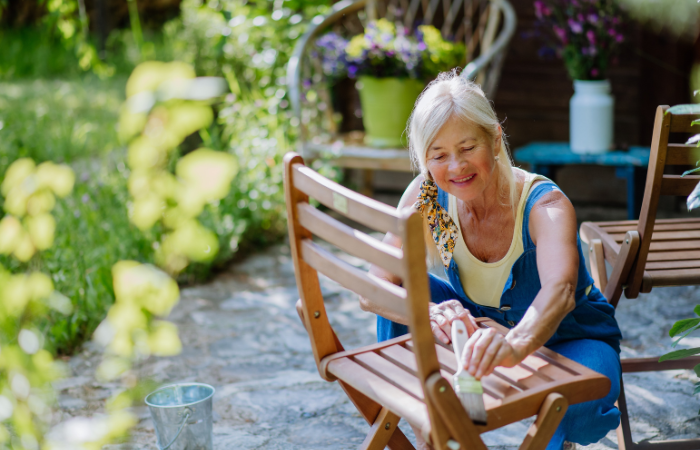starsza kobieta odnawiająca krzesła ogrodowe i szykująca sie na lato 