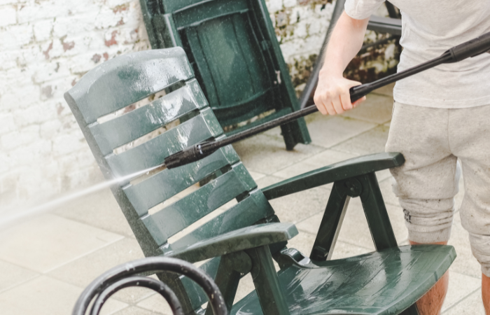 meżczyzna czyści zielone, plastikowe krzesło ogrodowe woda z kerszera