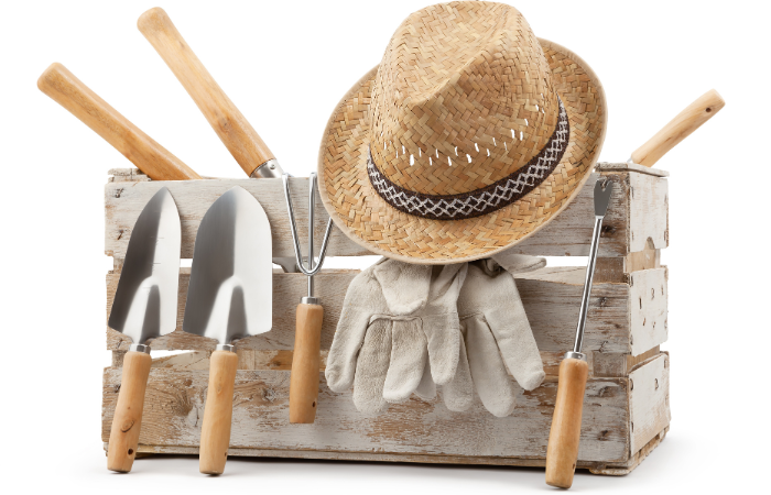 Zestaw narzędzi ogrodniczych, drewniana skrzynia z aluminiowymi narzędziami ogrodowymi, kielnia z drewnianą rączką, słomkowy kapelusz i rękawiczki ochronne, izolowane na białym tle.